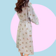 Long sleeve light blue robe with teddy bear pattern held by a person against a pink background. The robe is made of textured cotton 
