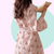 Long sleeve pink robe with teddy bear pattern held by a person against a pink background. The robe is made of textured cotton 