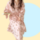 Long sleeve pink robe with teddy bear pattern held by a person against a pink background. The robe is made of textured cotton 