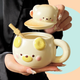Cute ceramic mug with a lid shaped like a bear. The mug is in a butter cream colour, and has a short straw on the side. 
