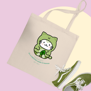 Tote bag with a green cat illustration and green sneakers on a pink background