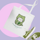 Tote bag with a green cat illustration and matching green sneakers on a purple and pink background