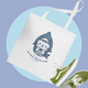 White tote bag with cute shark kitty illustration, blue text, and green sneakers, ideal for adding playful style to shopping. Tote bag