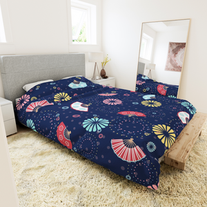 Bedding  with colourful fireworks in traditional Japanese pattern bedding with on a dark blue background. Several designs of Japanese paper fans are dotted around. The image is in the context of a bedroom interior