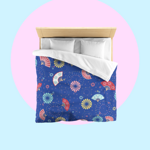 Bed with colourful fireworks in traditional Japanese pattern bedding with on a nippon blue background. Several designs of Japanese paper fans are dotted around