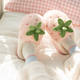 Pink plushy slippers that looks like strawberries finished in green plushy leafy stalk and seeds detail. Thick shoe sole with plush lining the interior, as worn by model with fluffy socks and wooly pyjama pants