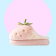 Pink plushy slippers that looks like strawberries finished in green plushy leafy stalk and seeds detail. This is the side profile of the slippers, showing how thick the sole is. 